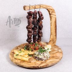 two skewered meats on a wooden plate with french fries