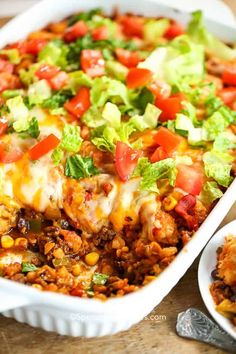 a casserole dish with chicken, lettuce, tomatoes and cheese on top