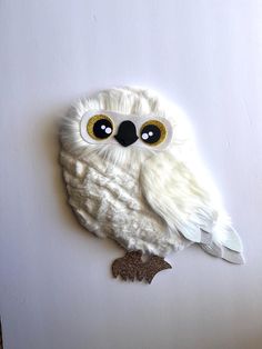 a white owl with big eyes sitting on top of a table