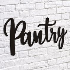 the word pantry written in black on a white brick wall next to a potted plant