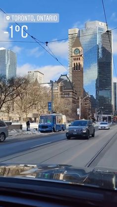 cars driving down the road in front of tall buildings