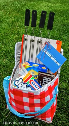 a red and white checkered bag with utensils in it on the grass