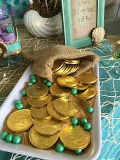 there is a bag full of gold coins and some green beads on the table next to it