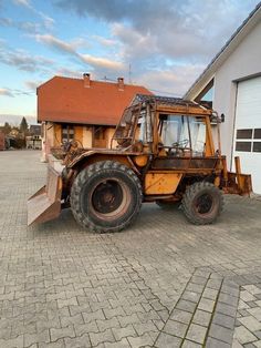 a large tractor parked in front of a building with a house on the other side