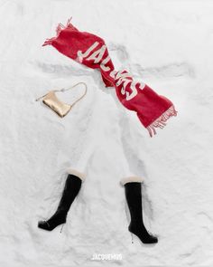 a woman is laying in the snow with her feet up wearing black boots and a red scarf