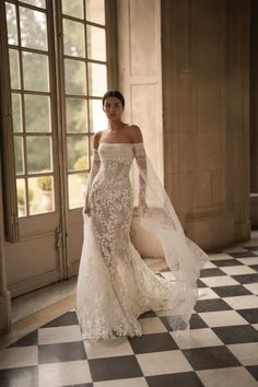 a woman in a wedding dress standing on a checkered floor with an open window