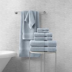 a stack of blue towels sitting on top of a table next to a bath tub