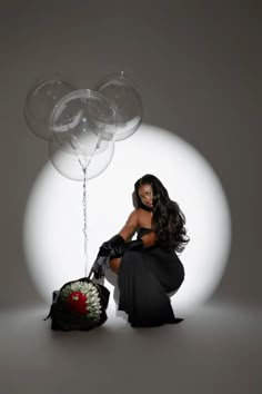 a woman sitting on the ground with balloons in front of her and an umbrella behind her