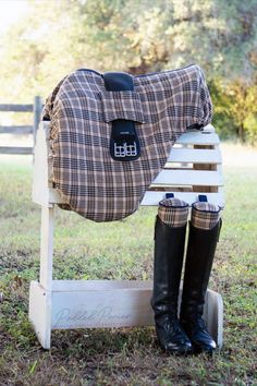 a woman sitting on top of a wooden bench next to a horse wearing riding boots