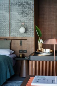 a bed room with a neatly made bed and a plant on top of the table