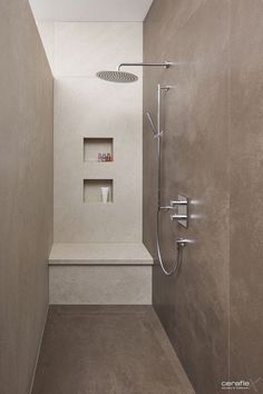 a walk in shower sitting next to a white sink under a skylight on top of a wall