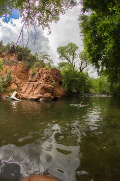 people are swimming in the river near some rocks