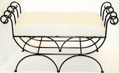 a black iron bench with a white cushion on it's back and two circles around the seat