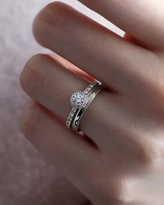 a woman's hand with a diamond ring on top of her finger and an engagement band