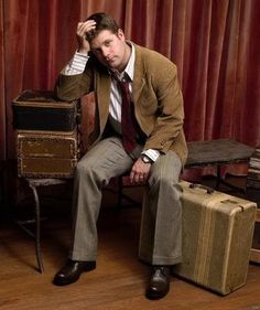 a man in a suit and tie sitting next to suitcases