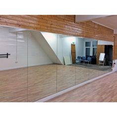 an empty room with wooden floors and large mirrors on the wall that reflect it's surroundings