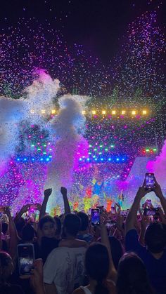 people are taking pictures with their cell phones as fireworks go off in the sky above them