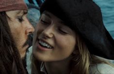 a man and woman dressed in pirate costumes looking into each other's eyes while standing next to each other