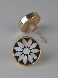 a black and white flower with gold trim on a pair of cufflinks, next to a screw