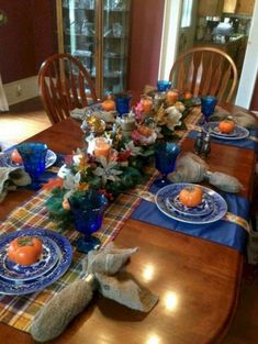 the table is set for thanksgiving dinner with blue dishes and plaid napkins on it