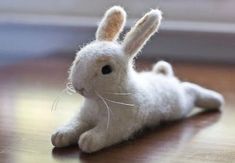 a white stuffed rabbit laying on top of a wooden table