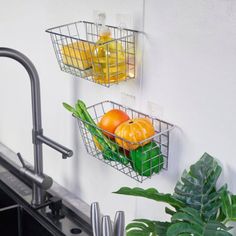 two metal baskets filled with oranges and lemons next to a kitchen faucet