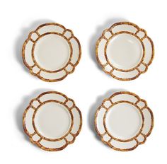 four white and gold plates sitting on top of each other in front of a white background