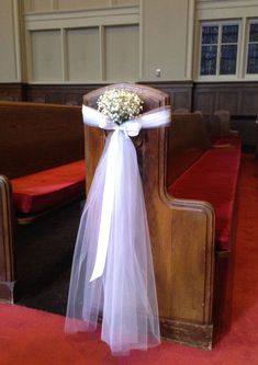 a church pew decorated with white flowers and ribbon