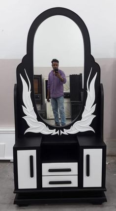 a man standing in front of a black and white dresser with a mirror on it