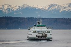 a large boat traveling across a lake with mountains in the background