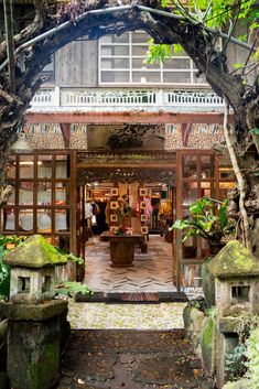 an entrance to a store with lots of plants and rocks in front of the building