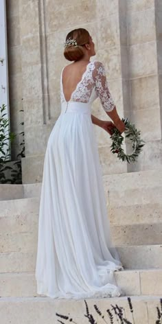 a woman in a white dress is standing on some steps with her back to the camera