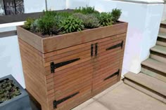 a wooden planter with plants growing out of it's sides on the side of a building