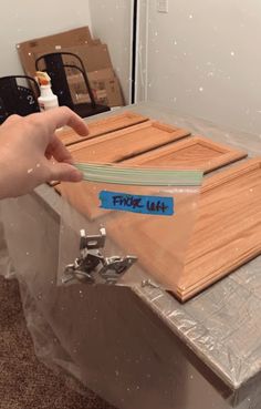 a person is holding a piece of wood on top of a metal table with some tape