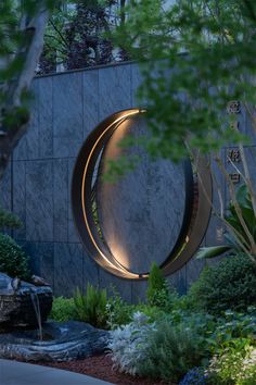 a circular sculpture in the middle of a garden with trees and bushes around it at night