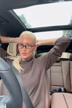 a woman sitting in the back seat of a car with her hands on her head