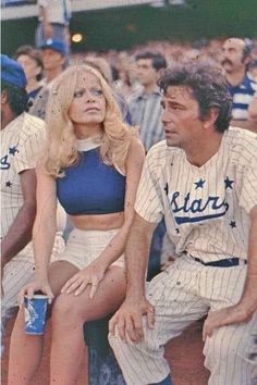 an old photo of a baseball player and a woman sitting next to each other at a game