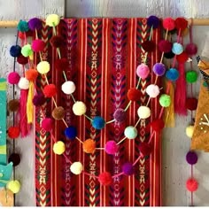 the colorful wall hanging is decorated with pom poms