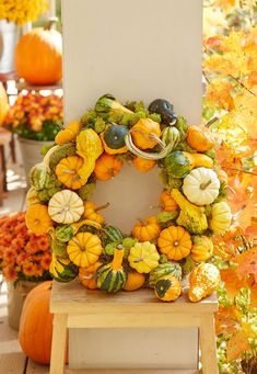 a wreath made out of pumpkins and gourds is sitting on a table