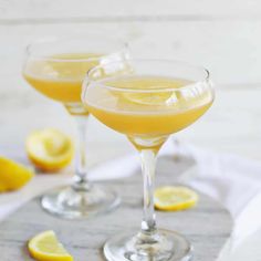 two glasses filled with lemonade sitting on top of a table