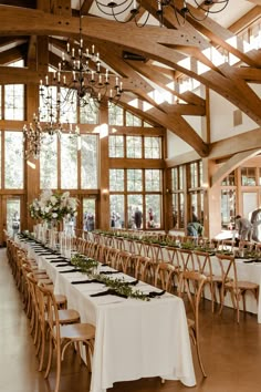 the tables are set up with white linens and greenery for an elegant wedding reception