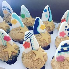 cupcakes decorated with surfboards and stars are on display