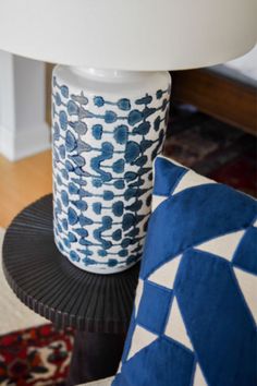 a blue and white vase sitting on top of a black table next to a lamp