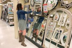 two women are looking at clocks in a store's glass display window and one is trying to decide which time it is