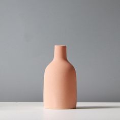 a pink vase sitting on top of a white table