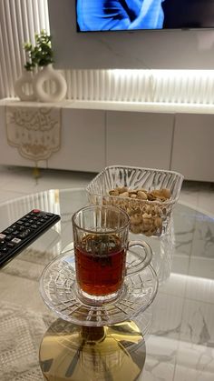 a cup of tea sitting on top of a glass table next to a remote control