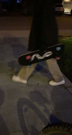 a skateboarder is walking down the sidewalk at night