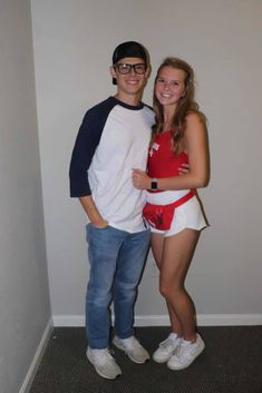 a man standing next to a woman in a red and white shirt with her arms around her chest