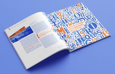 an open book with blue and orange letters on the front cover, sitting on top of a blue surface