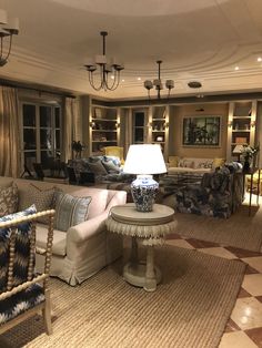 a living room filled with furniture and a lamp on top of a coffee table in front of a window